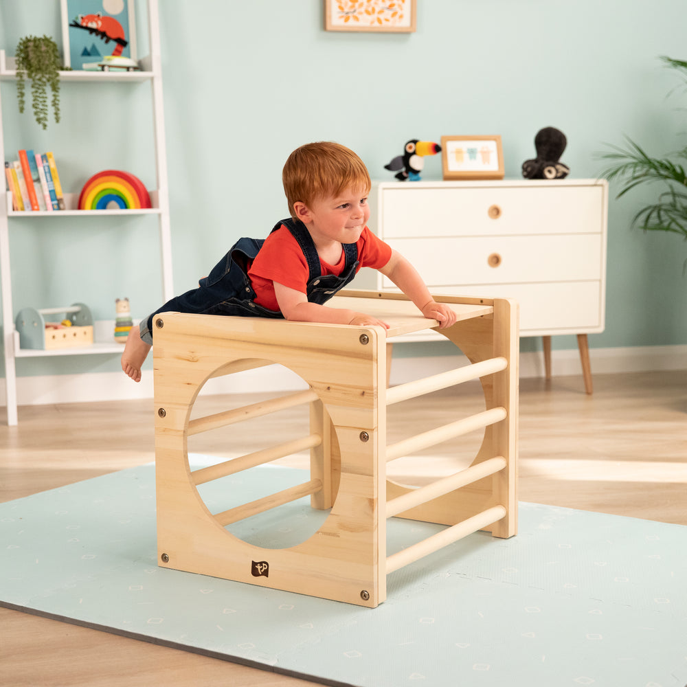 Child playing with wooden Pikler cube